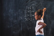 © Impact Photography - Mixed race elementary school girl solving math problems on chalkboard