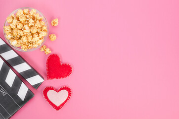 Valentine's Day movie concept. Movie clapperboard with hearts and caramel popcorn with copy space