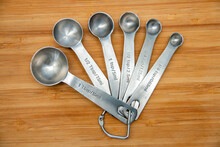 Silver measuring spoons on a wooden cutting board