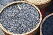 Closeup detail of a handwoven basket filled with striped sunflower seeds and other grains for sale at an outdoor market in Hanoi, Vietnam