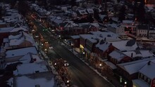 Cars, Trucks, Traffic On Street Through Town At Night. Christmas Lights And Snow Covered Rooftops In Winter. Aerial Drone View In Ephrata, PA, USA.