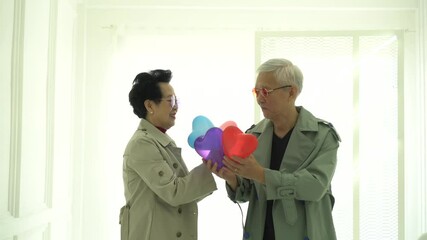 Wall Mural - Senior fashion model Asian couple express love happiness and relationship heart balloons
