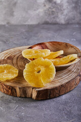 Canvas Print - Yellow candied pineapple rings on a gray concrete background on a wooden board. Dried fruits, Color trend 2021.