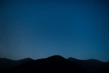 Wall Mural - silhouette of mountain range under dark blue night sky with many bright stars