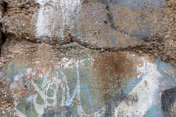 Wall Mural - Crumbling concrete aggregate wall with traces of paint in blue, green, and white, horizontal aspect