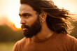 Long hair bearded young man portrait enjoying breezy wind in nature background.