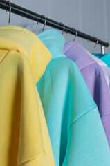 Multicolored hoodies on hangers in a sports store close up, clothing concept. Row of different hoodie ,long sleeve shirts , sweater on hangers.Modern show room selling clothes men, women children.