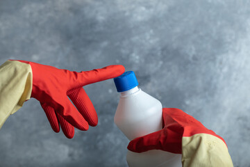 Wall Mural - Hands in red gloves touching tip of bleach
