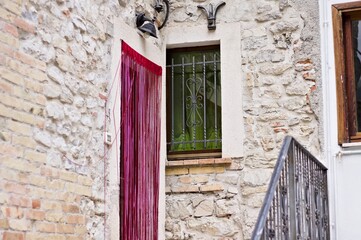 Wall Mural - A door with a red curtain near a window with a green curtain in an italian brick house (Marche, Italy, Europe)