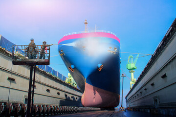 Manual Ship Wshin and Cleaning by water jet with front of Carrier ship wearing safety harness under ship repair on sleeper boat in the at floating dock background in shipyard