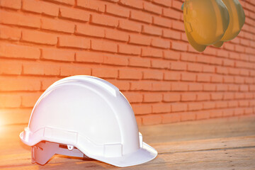 Wall Mural - White hard safety helmet hat for safety project of workman as engineer or worker on wooden floor and brick wall pattern background.