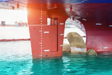 Shiopyard Ship mooring alongside in the sea with Propeller, rudder red waiting maintenance already by surveyor in floating dry dock on dark tone concept in shipyard Thailand