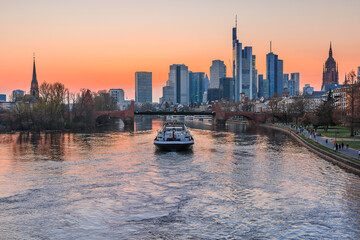 Wall Mural - The financial and business center of Frankfurt. City skyline in the evening at sunset with river Main. Park on the bank of the river. Ship on the river with bridge