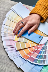 Wall Mural - Color wheel for choosing paint tone. Hands of female interior designer working with palette for choosing colors. Creative process concept. Comparing options with matching hues.