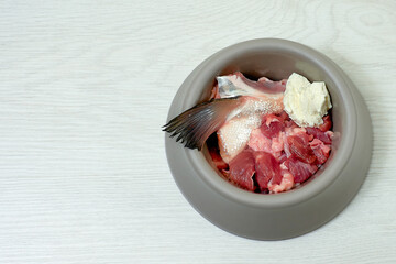 Wall Mural - Natural dog food in bowl on white floor. Raw fish, meat, cottage cheese. Healthy food for dogs. Copy space.
