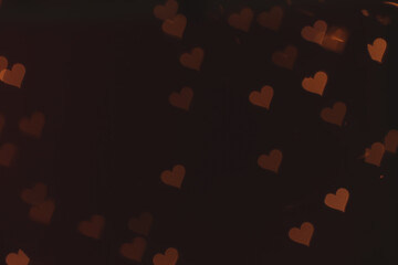 Blurred view of heart shaped lights on dark background. Bokeh effect