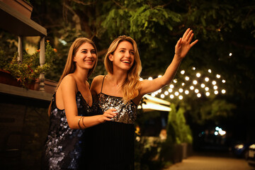 Canvas Print - Young women catching taxi on city street at night