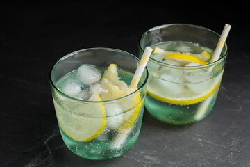 Soda water with lemon slices and ice cubes on grey table