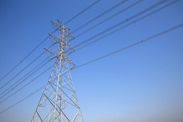 High-voltage transmission tower and electricity voltage wiring cable with sky background.