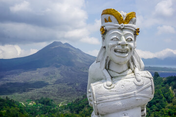 Balinese statue with a drum on the background of the Batur volcano