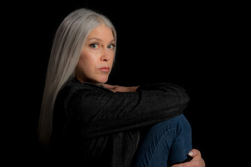 Wall Mural - Image of a beautiful mature blond woman in the studio. Studio image with a black background.