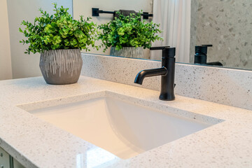 Close up of bathroom vanity with single white ceramic sink and black faucet