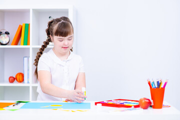 Wall Mural - A child with down syndrome sits above a picture of the sun's circle in class at a specialized school