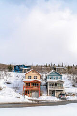 Canvas Print - Road along houses on snowy slope of a hill against cloudy sky during winter