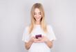 © Studio Nova - Excited young woman looking at her mobile phone smiling. Woman reading text message on her phone, isolated over white background.