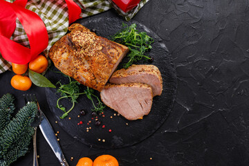 Wall Mural - a piece of baked pork with spices on a black plate and a dark background.