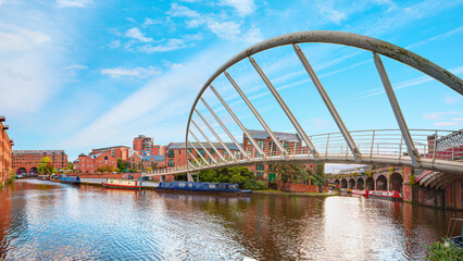 Waterway canal area with a narrowboat on the foreground modern bridge, Castlefield district - Manchester, UK