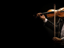 The violinist plays the violin on a dark background.