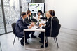 © sofiko14 - Business negotiations in office room. Team of attractive successful international corporate workers, sitting at the table while working together over business strategy of company
