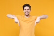 © ViDi Studio - Young smiling unshaved caucasian man 20s in casual blank print design t-shirt point index two fingers down on workspace copy space area look camera isolated on yellow background studio portrait.