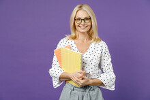 Smiling Gray-haired Blonde Teacher Woman Lady 40s 50s Years Old Wearing White Dotted Blouse Eyeglasses Standing Hold Notepads Looking Camera Isolated On Bright Violet Color Background Studio Portrait.