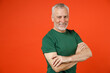 © ViDi Studio - Smiling elderly gray-haired mustache bearded man wearing basic casual green t-shirt standing holding hands crossed looking camera isolated on bright orange color wall background studio portrait.