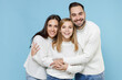 © ViDi Studio - Laughing funny young happy parents mom dad with child kid daughter teen girl in basic white sweaters hugging isolated on blue color background studio portrait. Family day parenthood childhood concept.