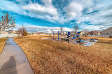 Wall Mural - Recreational park with childrens playground and shadow of a man on the pathway