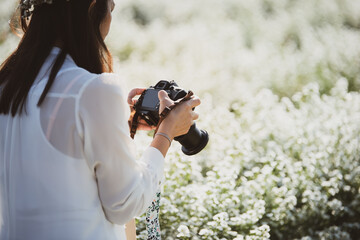 Outdoor lifestyle and hobby photography of a woman travel with Dslr camera in flower garden.