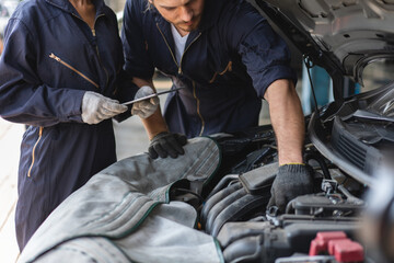 Two mechanics man and woman checking and repair maintenance a car in auto service garage