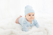 © Any Grant - a baby in blue clothes is lying on his stomach on a white rug