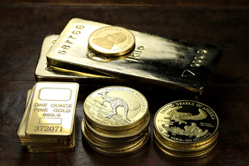 gold ingots an various bullion coins on wooden background