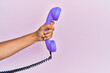 © Krakenimages.com - Hispanic hand holding vintage telephone over isolated pink background.