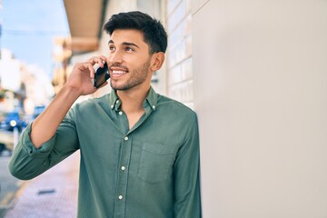 Young latin man smiling happy talking on the smartphone at the city.