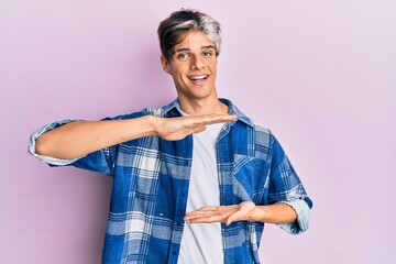 Young hispanic man wearing casual clothes gesturing with hands showing big and large size sign, measure symbol. smiling looking at the camera. measuring concept.