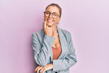 Poster - Beautiful caucasian woman wearing business jacket and glasses looking confident at the camera with smile with crossed arms and hand raised on chin. thinking positive.