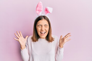 Sticker - Young beautiful woman wearing cute easter bunny ears celebrating mad and crazy for success with arms raised and closed eyes screaming excited. winner concept