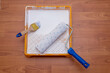 © branislav - Painting equipment on a floor: a paint tray with white paint, a paint roller and a paintbrush