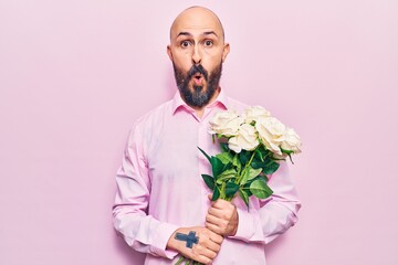 Poster - Young handsome man holding flowers scared and amazed with open mouth for surprise, disbelief face