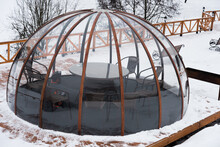 Transparent Housing In The Form Of A Dome, An Igloo. It's Winter, There's Snow All Around. Accommodation Is Waiting For Guests